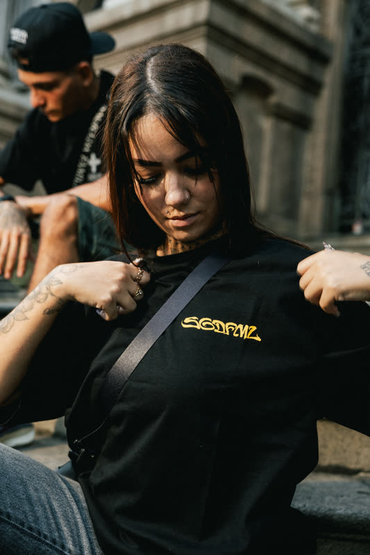 Close de modelo com lettering dourado na camiseta