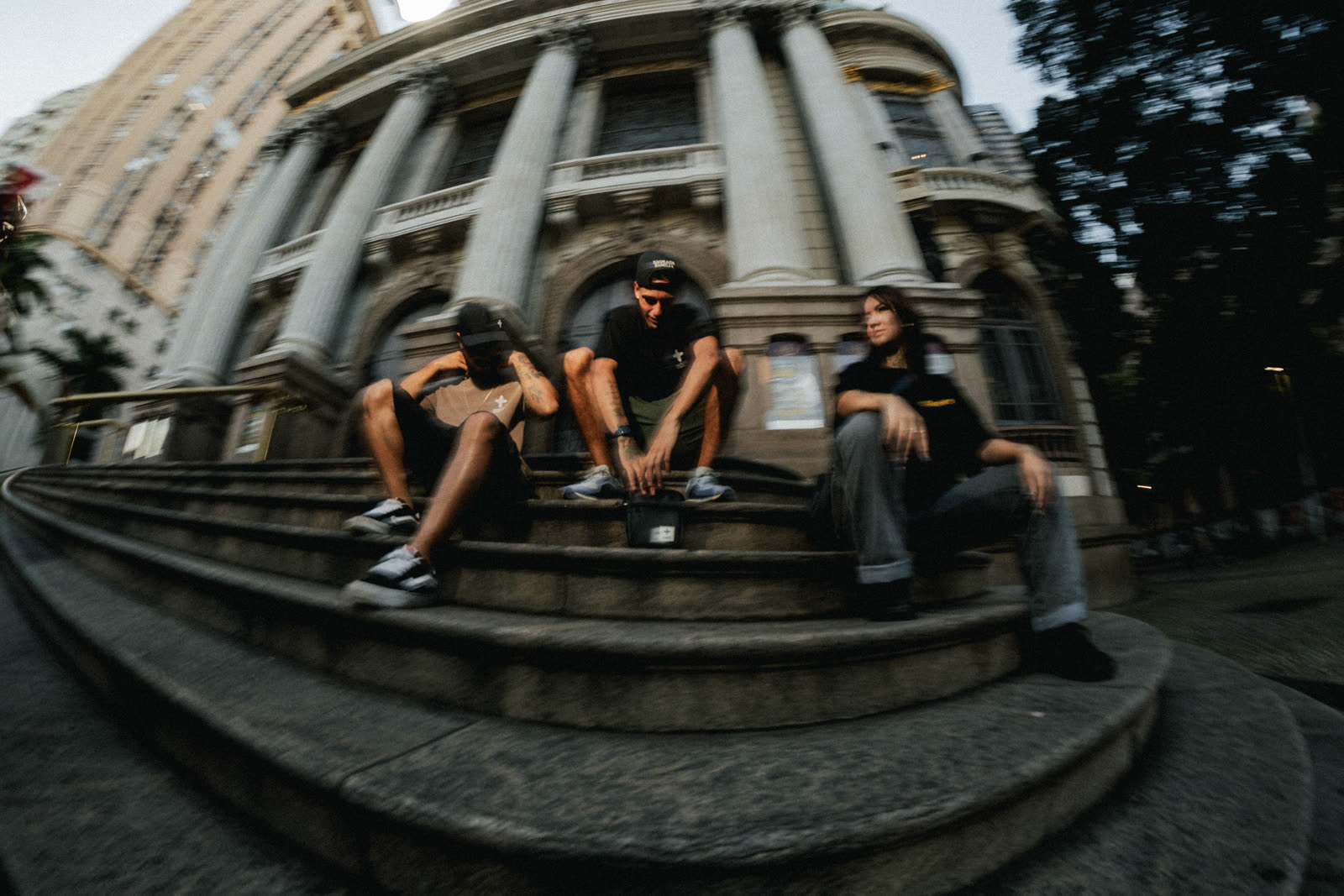 Trio de modelos na escadaria em lente olho de peixe, fachada monumental curvada